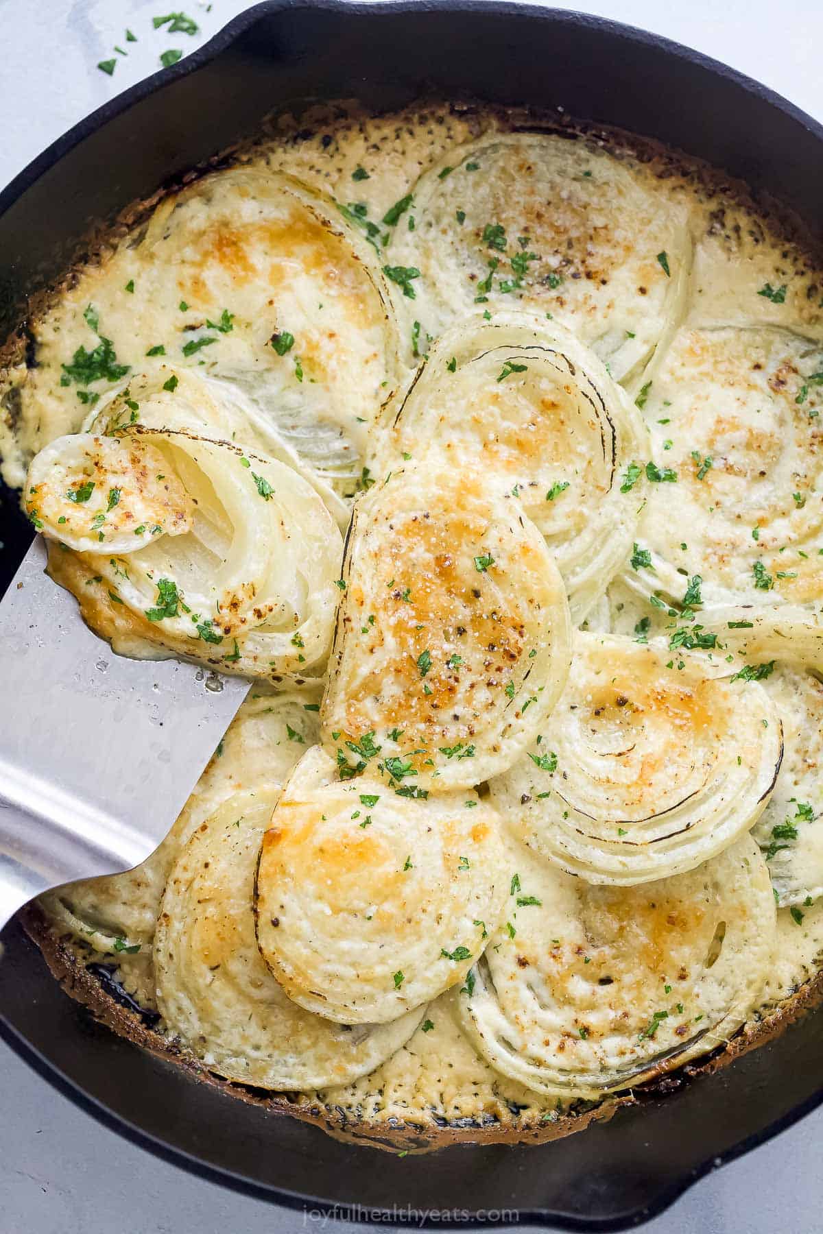 Grabbing some of the creamed onions recipe from the skillet with a spatula.