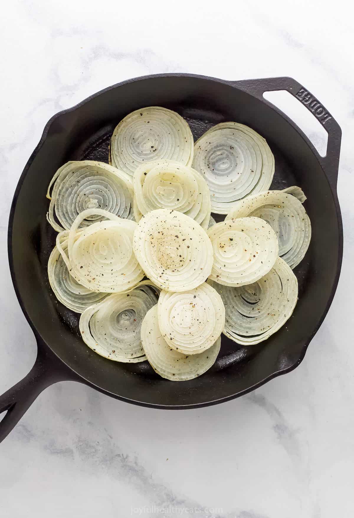 Layered baked onions in the skillet without sauce. 