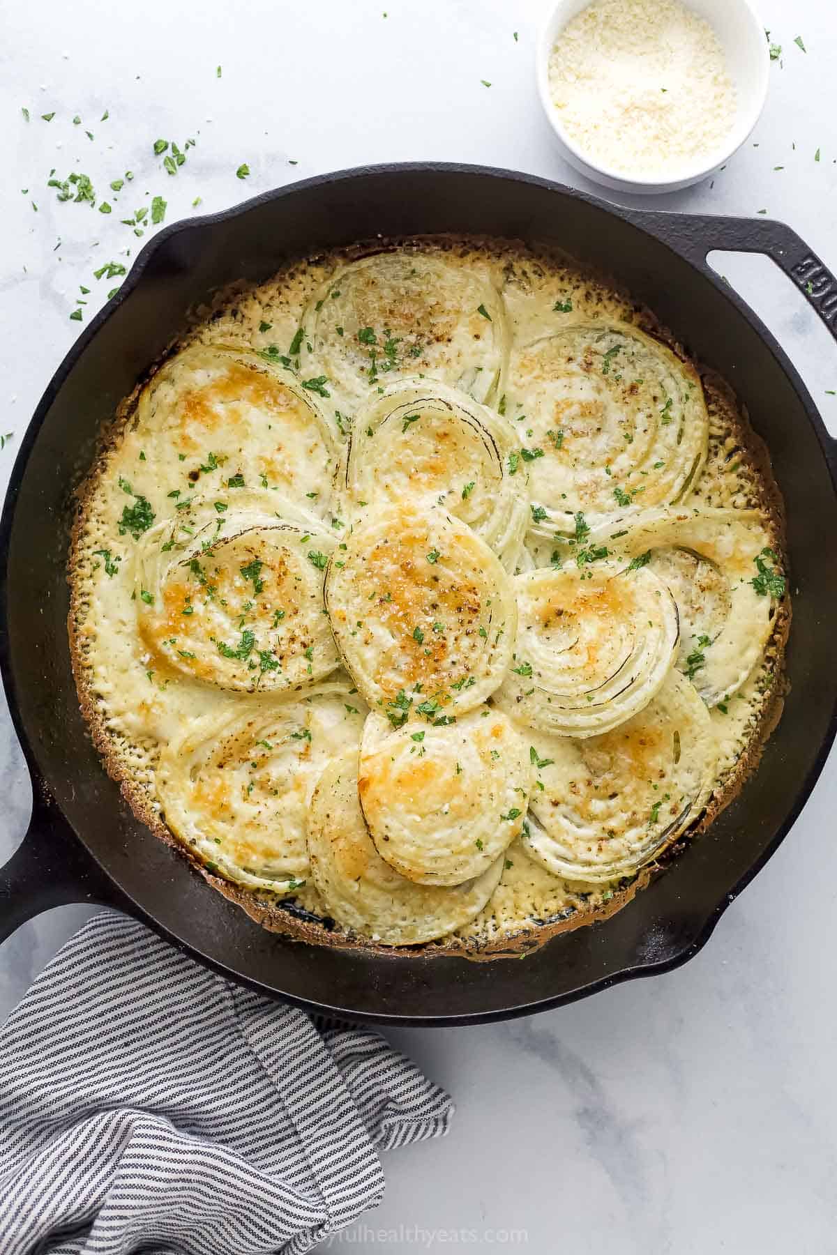 Overhead photo of the creamed onions with melty parmesan cheese in the skillet.