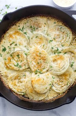 Cheesy creamed onions in the skillet with fresh parsley on top.