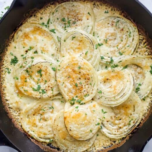 Cheesy creamed onions in the skillet with fresh parsley on top.