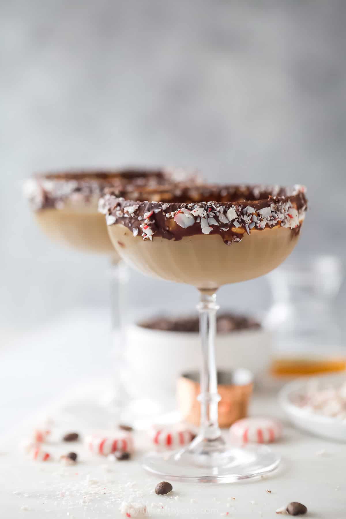 An icy peppermint espresso martini in a cocktail glass rimmed with dark chocolate and crushed peppermint candies. 