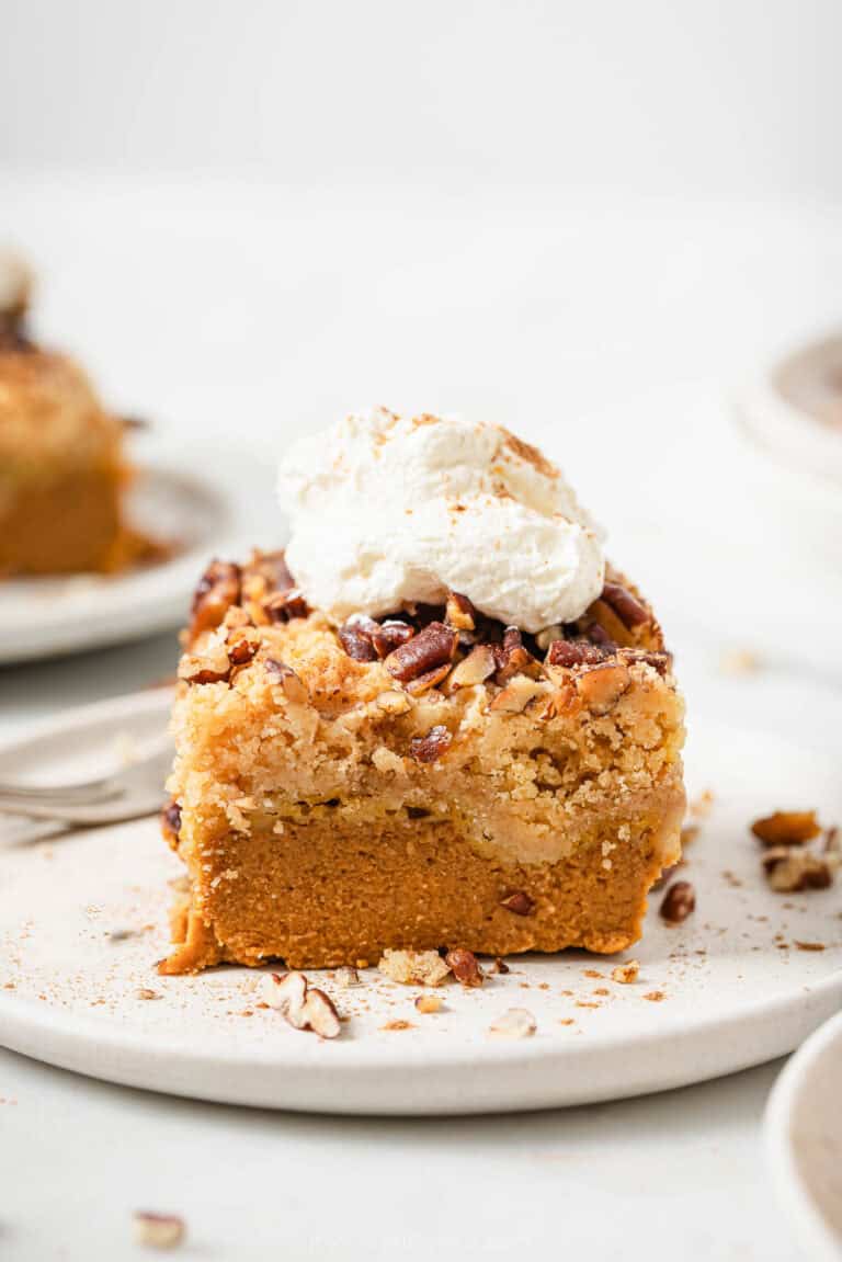 Sliced pumpkin dump cake with fluffy whipped cream and a sprinkle of cinnamon.