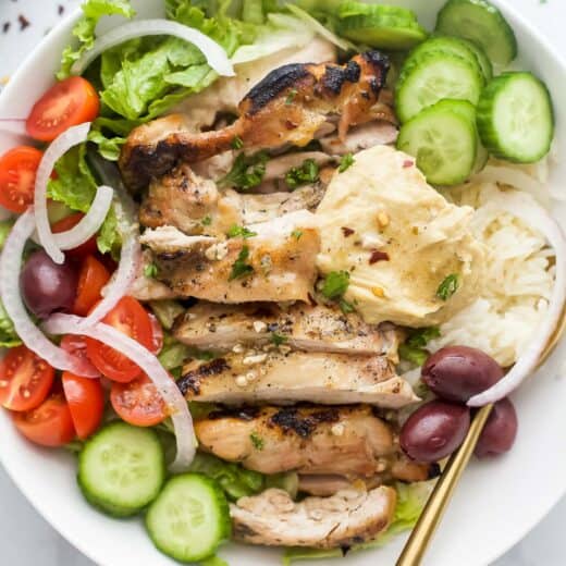 Greek chicken bowls with hummus, veggies, rice, and Greek vinaigrette.