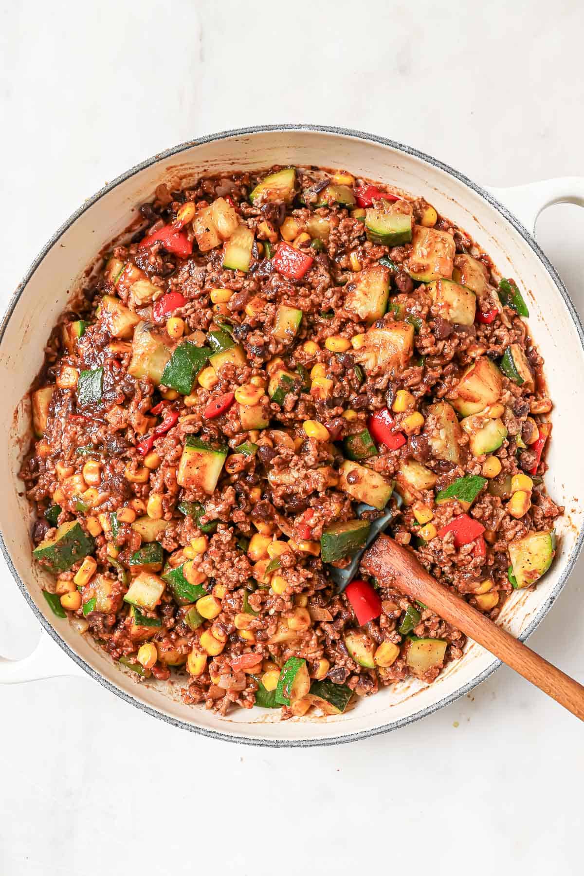 Adding the ground beef and sauce to the skillet. 