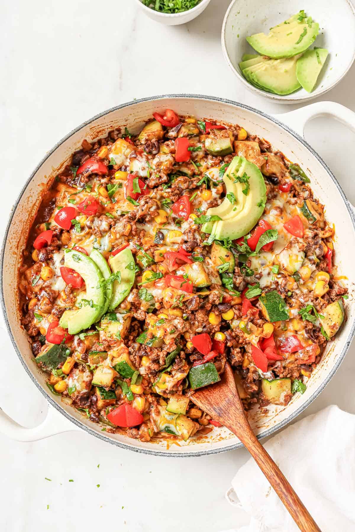 Ground beef and zucchini recipe with melty cheese, avocado, and tomatoes on top. 