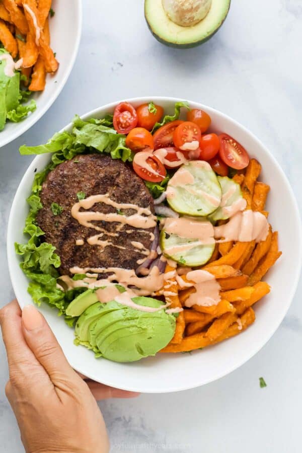 Overhead photo of a beef burger bowl with fresh veggies and sweet potato fries.