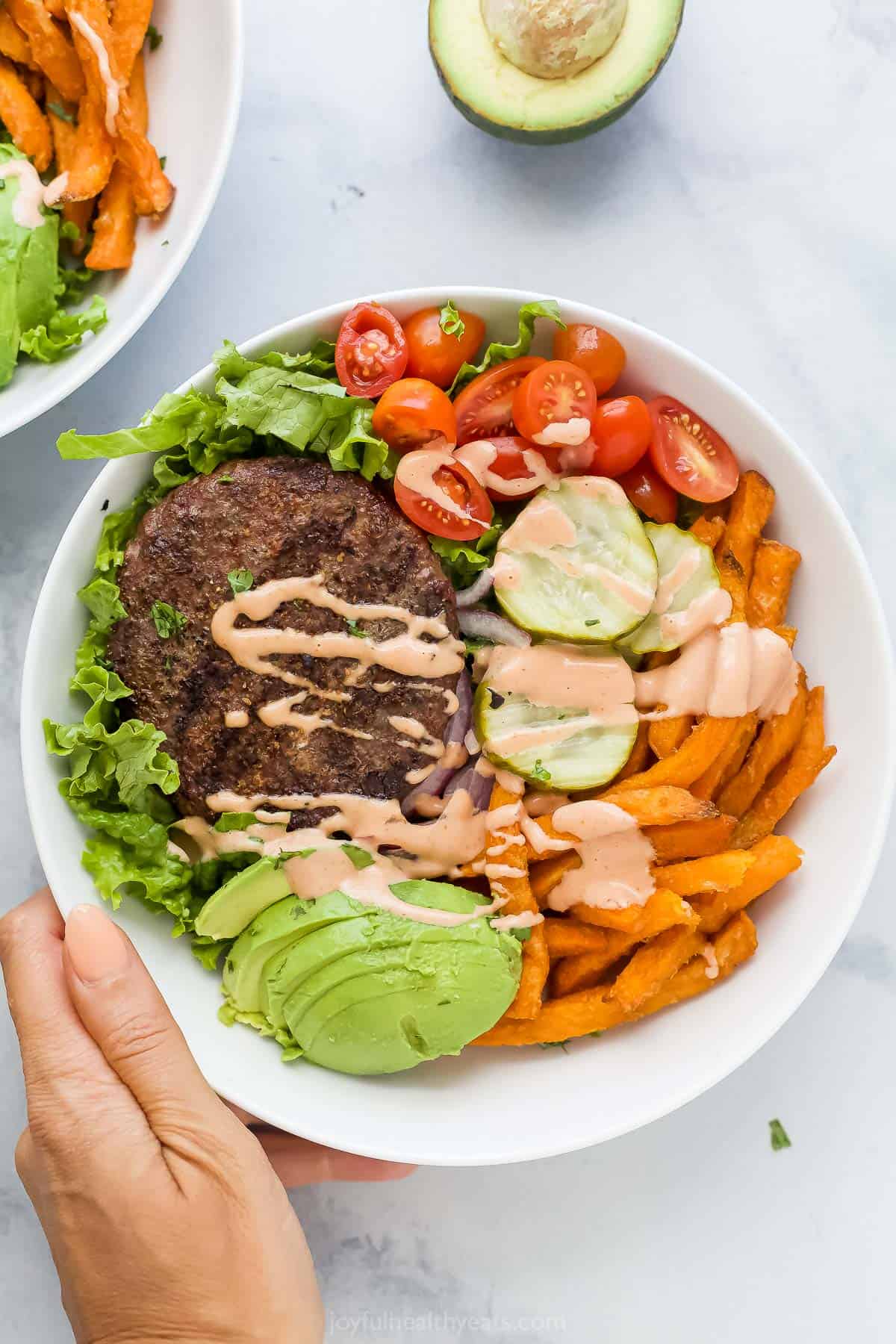 Overhead photo of a beef burger bowl with fresh veggies and sweet potato fries. 