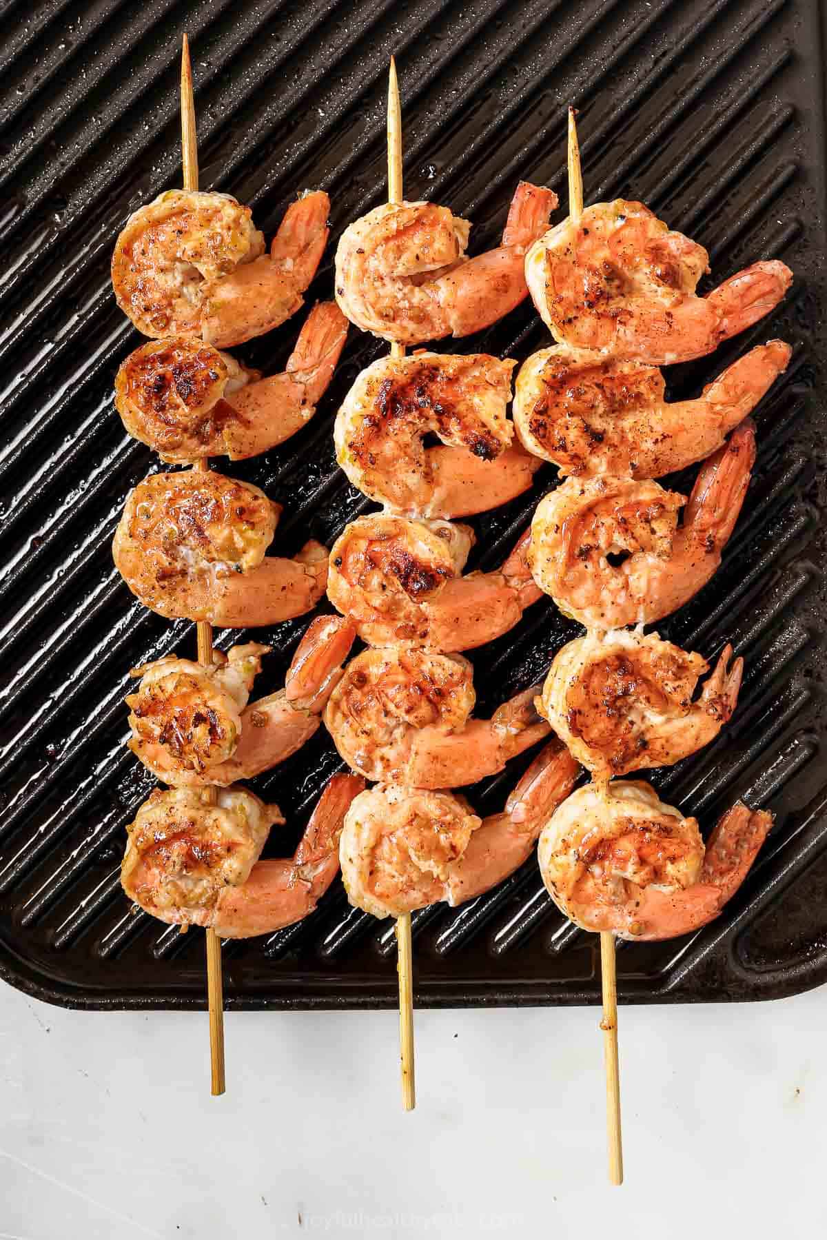 Cooking the shrimp on skewers over a grill. 