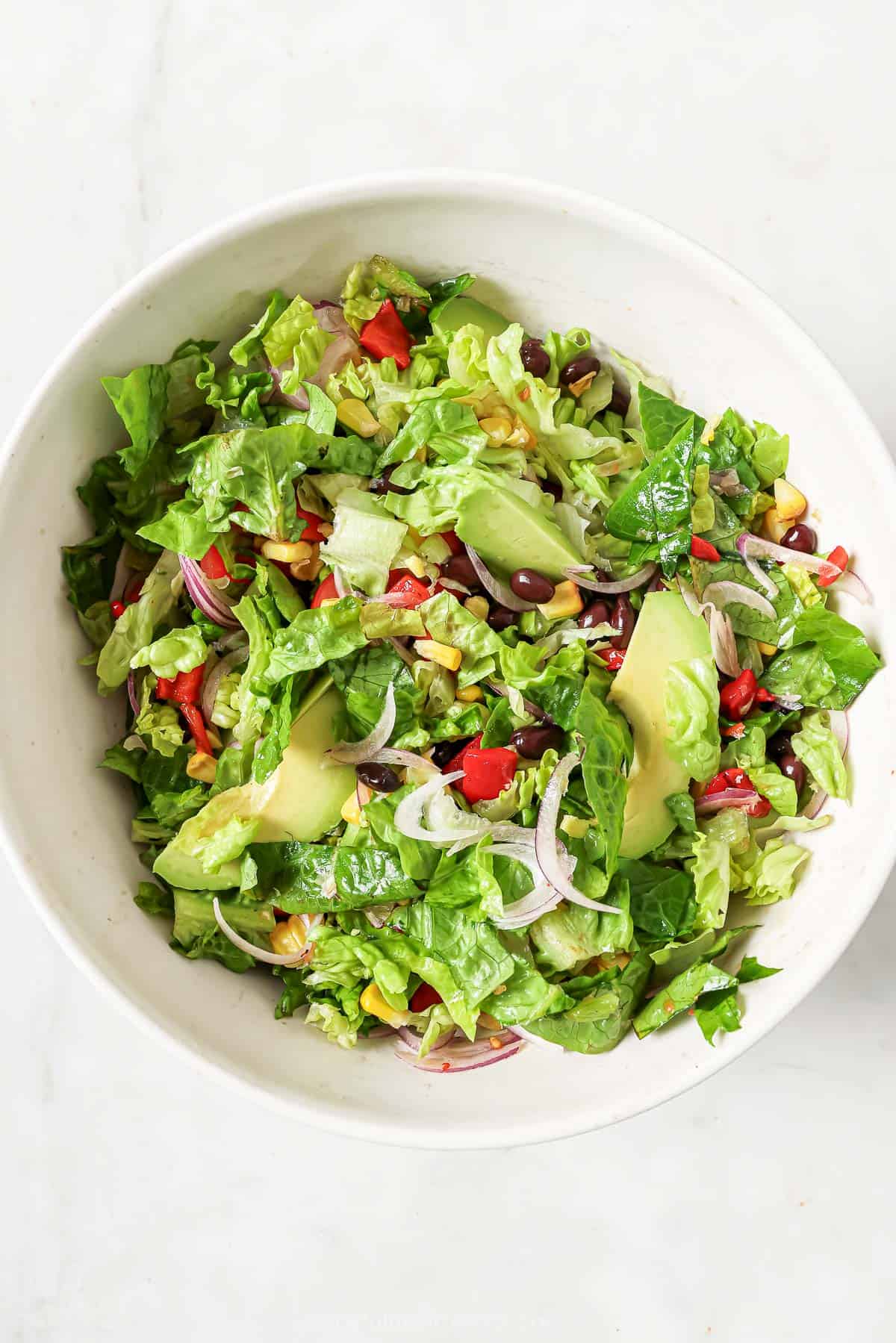 Adding the salad ingredients to a bowl. 