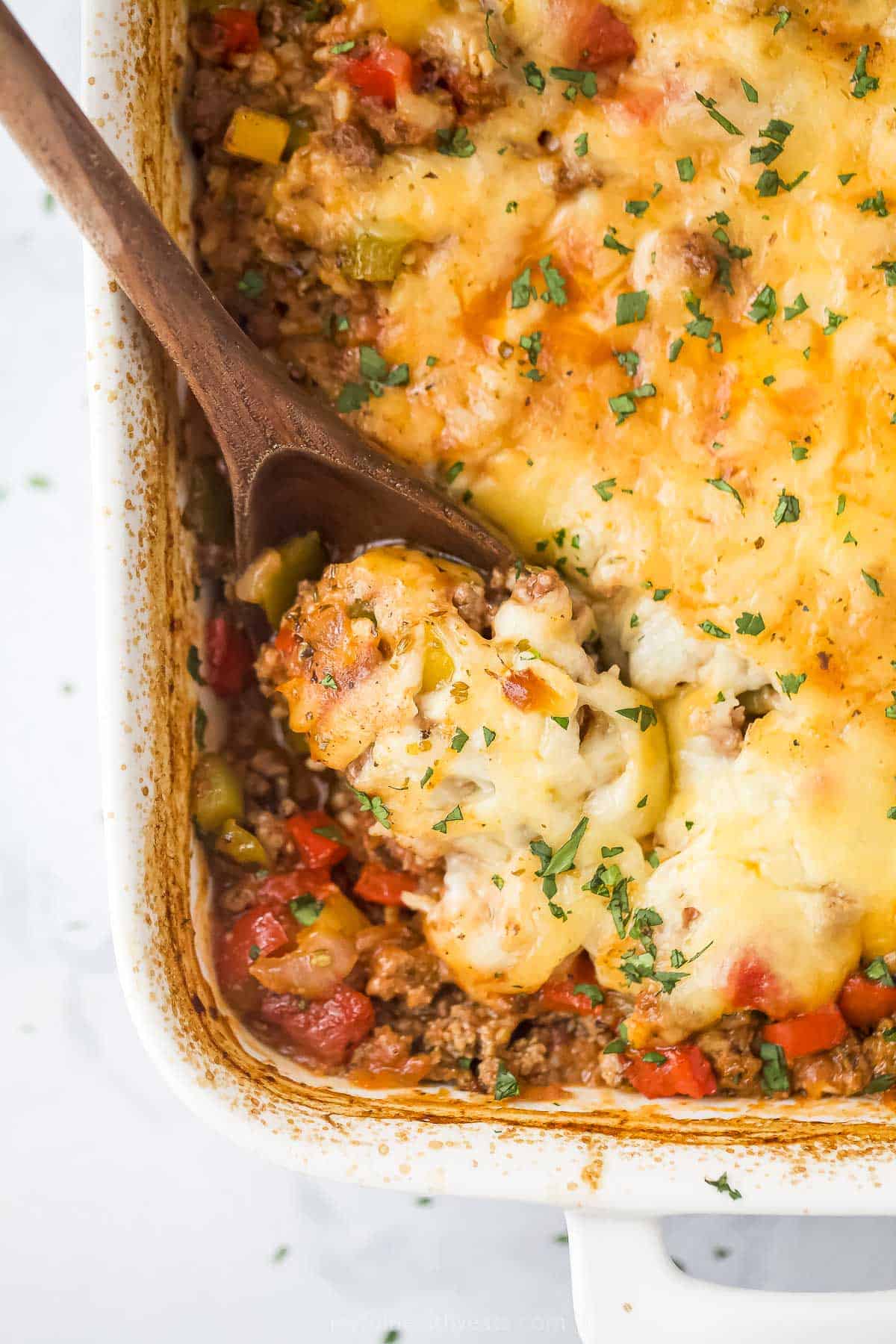 Grabbing some saucy, stuffed pepper casserole with a wooden spoon. 