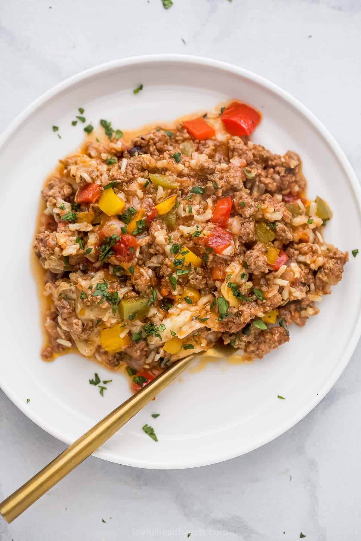 A serving plate of tomatoey beef and pepper casserole with melty cheese. 